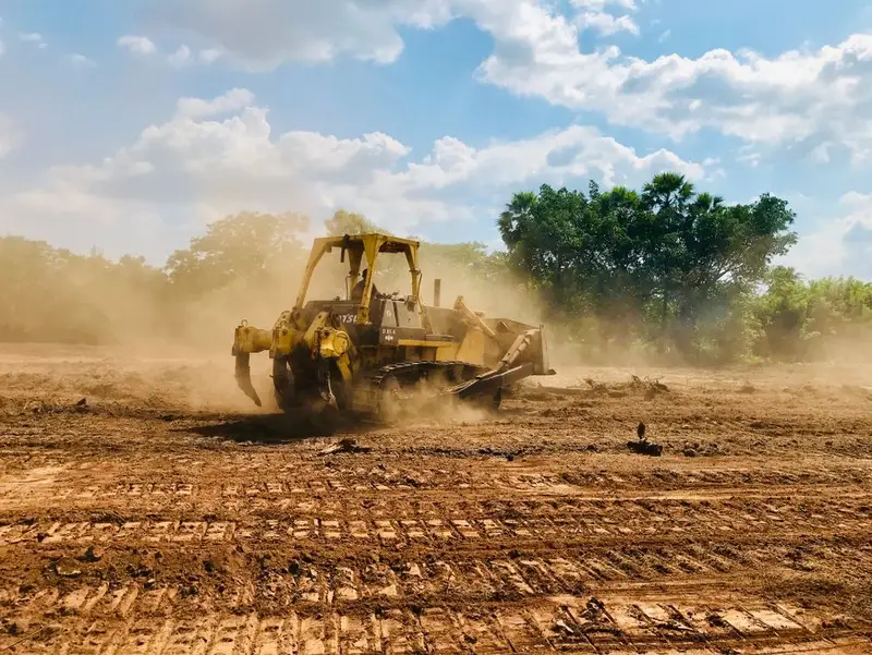 Yellow bulldozer kicking up dust as it rips and grades a dirt site