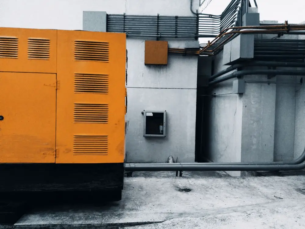 Orange enclosed generator set installed beside a building