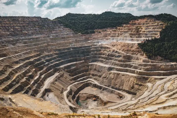 Terraced benches of a deep open-pit mine cut into a forested hillside