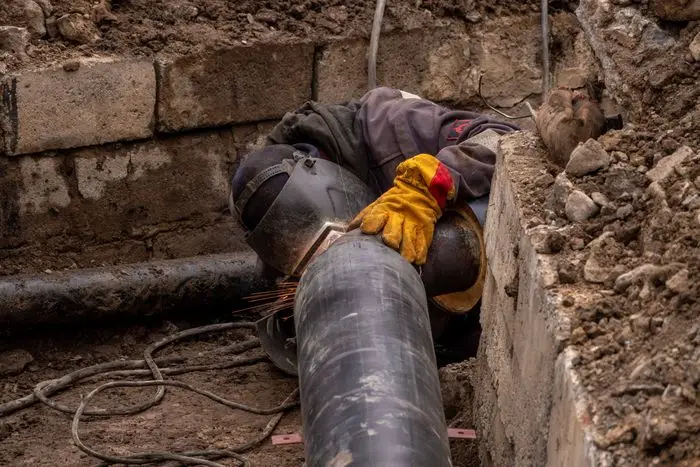 Welder in a trench working on a buried steel pipeline