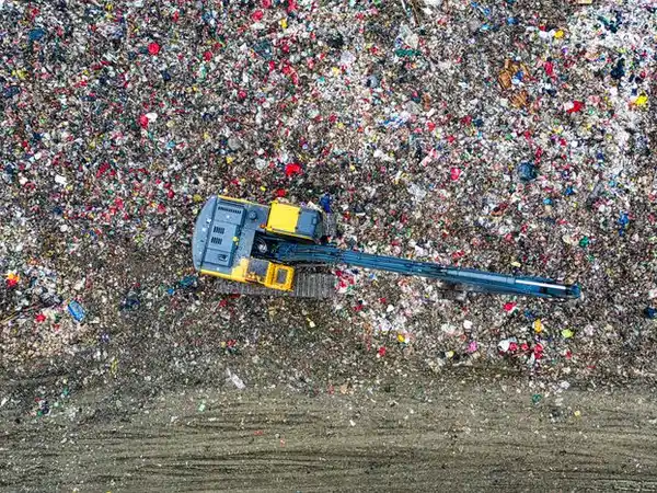 Aerial view of an excavator spreading mixed waste at a landfill